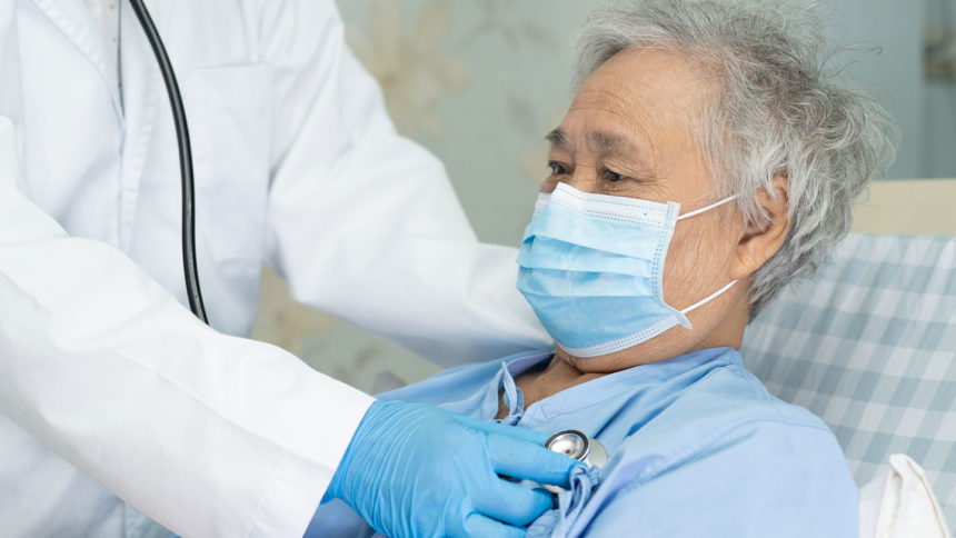 Closeup image of older adult patient in bed being checked by doctor with stethoscope; Credit: Getty Images