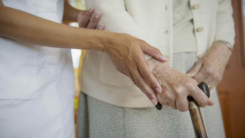 Close up image of a caretaker helping older woman walk